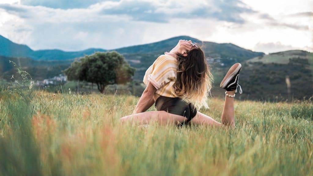 A young woman stretching outdoors in morning sunlight symbolizing healthy daily habits.