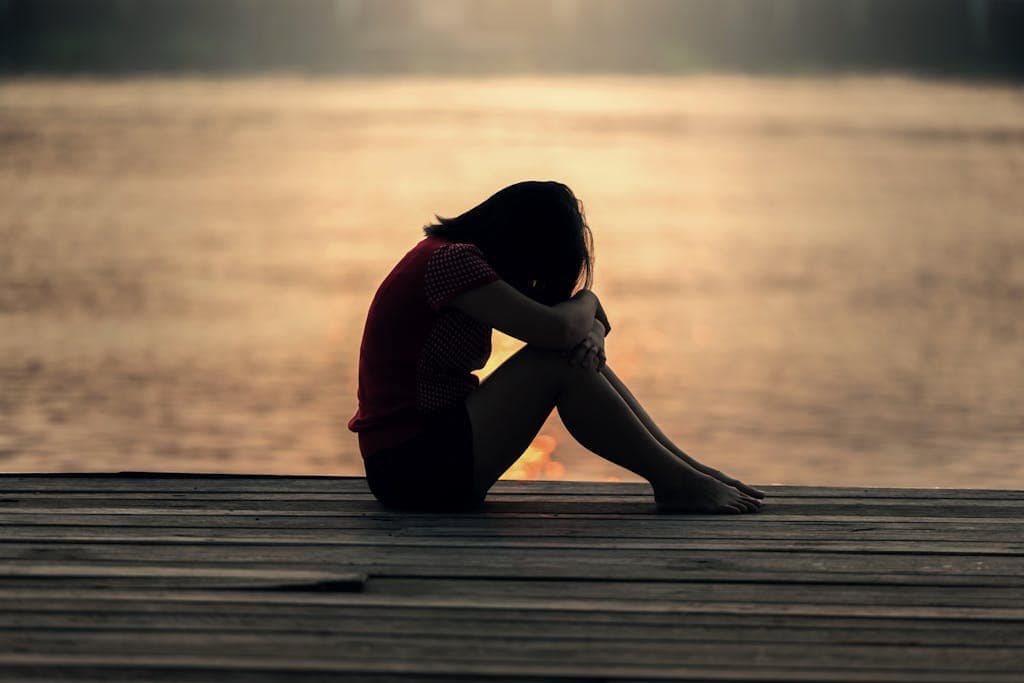 Woman sitting quietly during sunset reflecting on life direction.