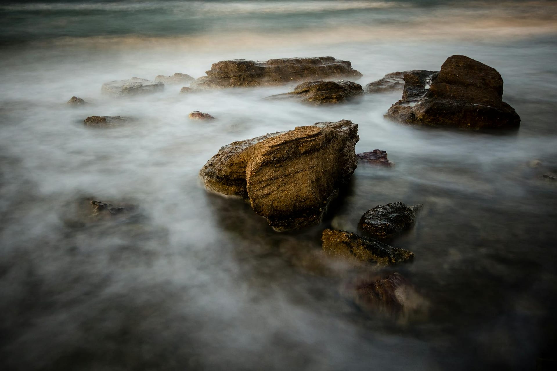 Serene coastal scene with rocks and misty ocean water, evoking tranquility.