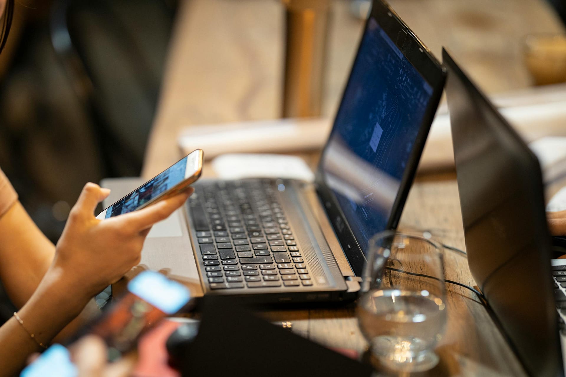 Woman sharing content on social media using a phone and laptop.