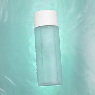 A clear bottle floats on vibrant turquoise water, creating a serene aesthetic.