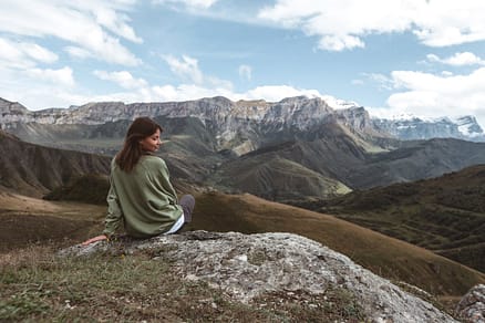 A young woman on a mountain viewpoint looking over a wide landscape.